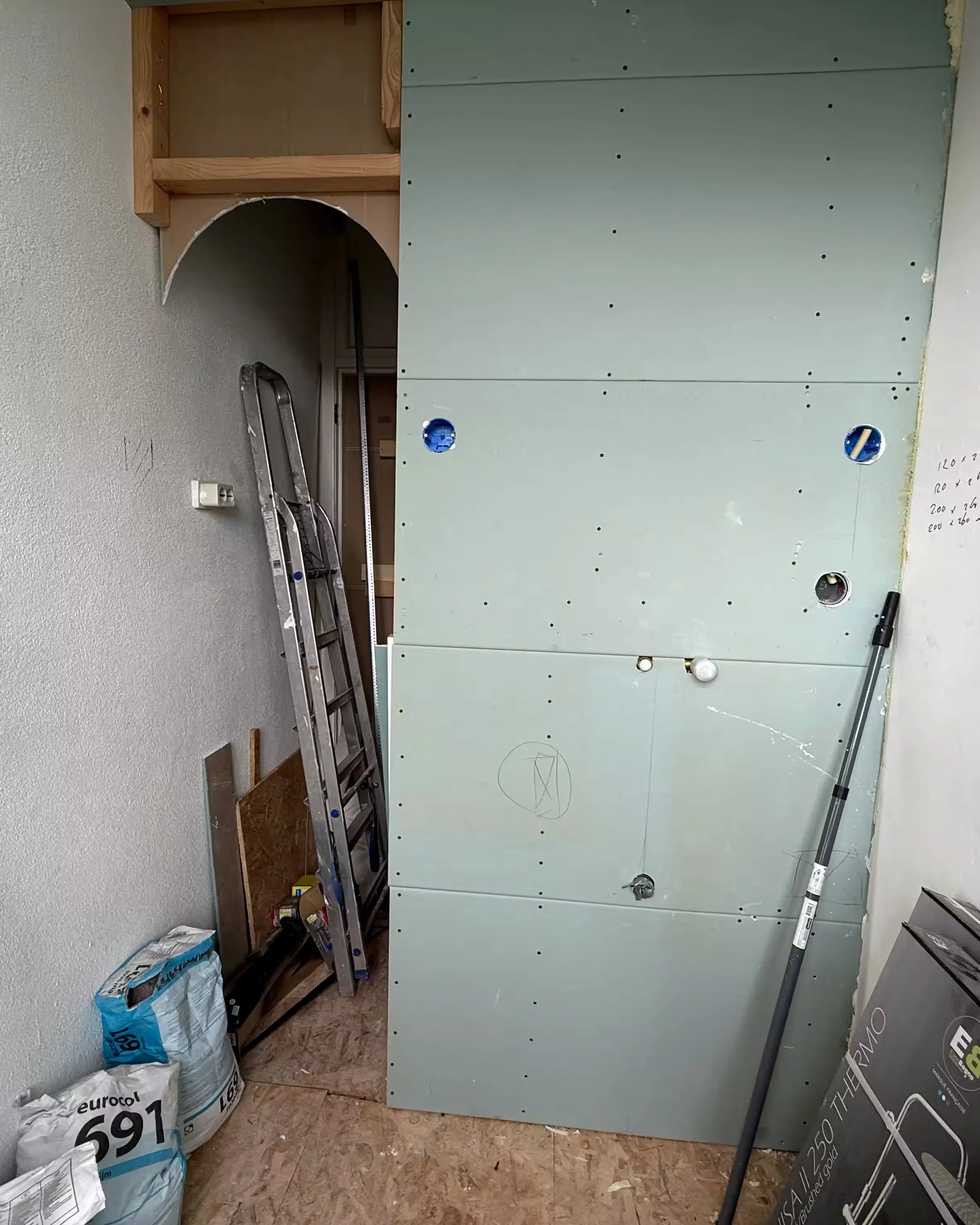 De badkamer van Maj-Britt tijdens de bouw: kale wanden, ladders en bouwafval, achtergelaten door de vorige aannemer