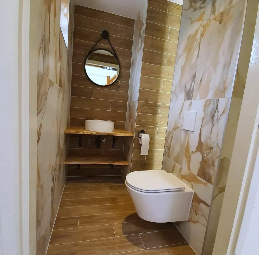 Toilet met wanden in onyxlook, een houten plank met een witte fontein en een ronde spiegel aan een leren band